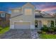 Charming two-story home featuring a brick driveway, two-car garage, and elegant front porch with a black front door at 1909 Donahue Dr, Ocoee, FL 34761