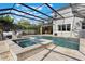 Backyard pool and spa area with screened enclosure, tile flooring, and lounge furniture at 1909 Donahue Dr, Ocoee, FL 34761