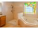 Bathroom featuring a walk-in shower, soaking tub, double vanity, and stained glass window at 1949 Tiptree Cir, Orlando, FL 32837