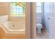 Bathroom with a soaking tub beneath a stained glass window, and adjacent toilet area at 1949 Tiptree Cir, Orlando, FL 32837