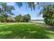 Spacious backyard featuring lush green lawn and mature trees, with a serene lake view in the distance at 195 E Faith Ter, Maitland, FL 32751