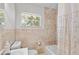 Cozy bathroom with neutral stone tiling, tub, and a bright window at 2707 E Marks St, Orlando, FL 32803