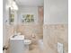 Cozy bathroom with neutral stone tiling, tub, and a bright window at 2707 E Marks St, Orlando, FL 32803