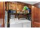 Small laundry room featuring a washer, dryer, shelving, and wood-look walls at 2707 E Marks St, Orlando, FL 32803