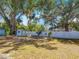 Expansive backyard featuring mature trees, white vinyl fence, and a storage shed, offering ample space for outdoor activities at 288 N Seneca St, Daytona Beach, FL 32114