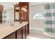 Bathroom featuring a vanity with double sinks, a tub with a shower, and a decorative window at 343 Raleigh Pl, Oviedo, FL 32765