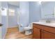 Bright bathroom featuring a toilet, vanity with sink, and blue walls with wood-look floors at 5839 Tarleton Way, Mount Dora, FL 32757
