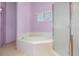 Inviting bathroom with garden tub, tiled tub surround, separate shower, and large window providing natural light at 6019 Long Peak Dr, Orlando, FL 32810