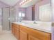 Well-lit bathroom with double sinks, wood vanity, and a sleek glass-enclosed shower for a modern and clean aesthetic at 6019 Long Peak Dr, Orlando, FL 32810