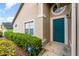 Home exterior showcases a turquoise front door, lush shrubs, and well-kept landscaping at 6019 Long Peak Dr, Orlando, FL 32810