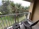 Condo balcony with patio furniture and relaxing views of swaying palm trees and lush foliage at 6403 Parc Corniche Dr # 4308, Orlando, FL 32821