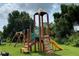 Community playground with climbing structure, slide, and swings surrounded by green grass and mature trees at 6403 Parc Corniche Dr # 4308, Orlando, FL 32821