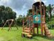 Community playground with climbing structure, slide, and swings surrounded by green grass and mature trees at 6403 Parc Corniche Dr # 4308, Orlando, FL 32821