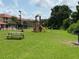 Community playground with slide, climbing structure, picnic tables, and barbecue grills on a grassy lawn at 6403 Parc Corniche Dr # 4308, Orlando, FL 32821