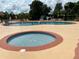 Community pool area featuring a hot tub, zero entry pool, lounge chairs, and a lush tropical landscape at 6403 Parc Corniche Dr # 4308, Orlando, FL 32821