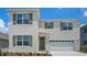 Two-story home with a white exterior, green shutters, a two-car garage, and a well-maintained front yard at 699 Griffon Ave, Lake Alfred, FL 33850