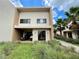 Modern two-story villa showcasing clean lines, a covered patio, and lush landscaping with palm trees at 7458 Brooklyn Dr, Kissimmee, FL 34747