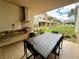Covered outdoor patio with a built-in grill, dining table, and view of the lawn at 7458 Brooklyn Dr, Kissimmee, FL 34747