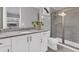 Well-lit bathroom featuring a granite countertop, frameless shower and white cabinets at 7584 Marker Ave, Kissimmee, FL 34747
