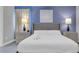 Serene bedroom with blue accent wall, featuring a plush bed and stylish bedside lamps at 7584 Marker Ave, Kissimmee, FL 34747