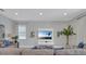 Bright living room featuring neutral tones, a mounted television, modern decor, and large windows at 7584 Marker Ave, Kissimmee, FL 34747