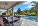Outdoor living space with a covered patio, dining area, pool, and spa surrounded by tropical landscaping at 7584 Marker Ave, Kissimmee, FL 34747