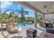 Covered patio area with lounge chairs, outside dining table set, hanging chair, and pool views at 7584 Marker Ave, Kissimmee, FL 34747