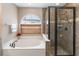 Bright bathroom featuring a soaking tub with a window and a tiled shower at 905 N Lake Claire Cir, Oviedo, FL 32765