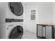 Efficient laundry room with stacked washer/dryer, stylish tiled floor, and modern storage cabinet at 908 Tilden Oaks Trl, Winter Garden, FL 34787
