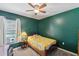 Cozy bedroom with a bright yellow quilt, complemented by a ceiling fan and natural lighting at 97 Desiree Aurora St, Winter Garden, FL 34787