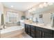 Charming bathroom featuring double sinks, dark cabinets, and a separate tub with tiled backsplash at 1065 Clifton Springs Ln, Winter Springs, FL 32708