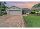 Charming home featuring a brick driveway, attached garage, and well-maintained lawn at sunset at 1096 Dees Dr, Oviedo, FL 32765