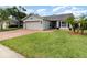Well-manicured front yard featuring lush green grass, palm trees, and a brick paver driveway at 1096 Dees Dr, Oviedo, FL 32765