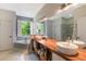 Bright bathroom featuring double sinks with wood vanity, soaking tub, and a large mirror reflecting a glass shower enclosure at 11878 Via Lucerna Cir, Windermere, FL 34786