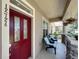 Cozy front porch features a vibrant red door, comfortable seating and decorative plants offering a relaxing outdoor space at 12724 Bideford Ave, Windermere, FL 34786
