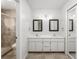 Bathroom with double sinks, framed mirrors, vanity lighting, and glass shower with tiled floors at 135 Heron Bay Cir, Lake Mary, FL 32746