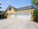 Exterior of yellow home featuring an attached three-car garage with white doors and concrete driveway at 1448 Conway Isle Cir, Belle Isle, FL 32809