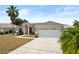 Inviting single-story home with a spacious driveway, two-car garage, and a lush palm tree in the front yard at 15 Sawfish Ln, Kissimmee, FL 34759