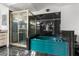 This is a luxurious bathroom featuring black tile walls, a unique shower, and a teal colored tub at 16500 Quarter Horse Ct, Montverde, FL 34756