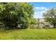 View of backyard with green grass, mature trees and a scenic pond in the background at 1821 San Jacinto Cir, Sanford, FL 32771