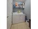 A well-kept laundry room with tile floors, washer, dryer, and shelving for storage at 204 Terrace Ridge Cir # 204, Davenport, FL 33896