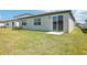 Exterior view of a home's backyard with green grass, a patio, and a sliding glass door at 2141 Rosewood Dr, Bartow, FL 33830