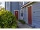 Exterior view of a blue condo building with brick-red doors, shrubs, and a sidewalk at 242 Coco Plum Dr, Davenport, FL 33897