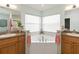 Bright bathroom featuring dual sinks, a corner tub, and linen closets at 2420 Heron Ct, St Cloud, FL 34769