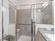 Modern bathroom with a glass shower, granite countertop, shower bench, and grab bar for accessibility at 2423 Datura Loop, St Cloud, FL 34772