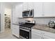 Well-equipped kitchen showcasing granite countertops, stainless steel appliances, white cabinetry, and adjacent pantry access at 2423 Datura Loop, St Cloud, FL 34772