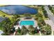 An aerial view of a community pool nestled by a lake with lounging chairs and palm trees at 2423 Datura Loop, St Cloud, FL 34772