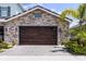 Exterior stone garage with modern wood door, pavers, and well-maintained landscaping at 3078 Isles Way, New Smyrna Beach, FL 32168