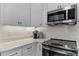 Close-up of the kitchen features stainless steel appliances, solid surface countertops, and tile backsplash at 3078 Isles Way, New Smyrna Beach, FL 32168