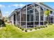 A screened patio sits on a meticulously maintained lawn with manicured bushes and palm trees at 3078 Isles Way, New Smyrna Beach, FL 32168